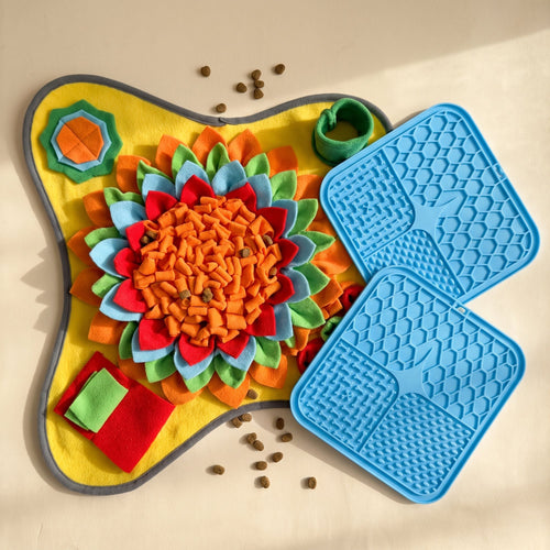 Snuffle mat and two blue lick mats laid flat on a cream table with scattered dog kibble